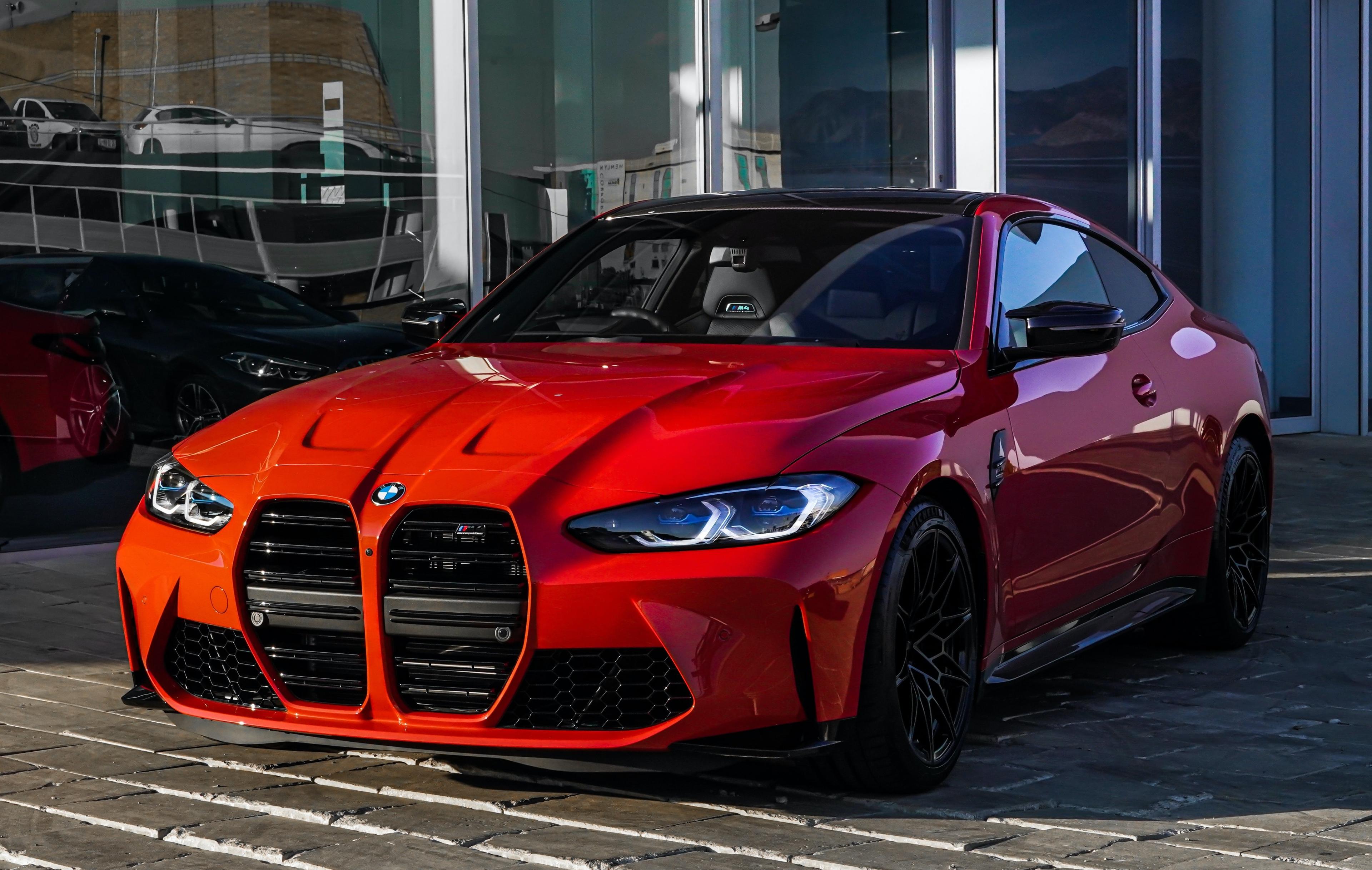 BMW M4 rouge garée devant une vitrine